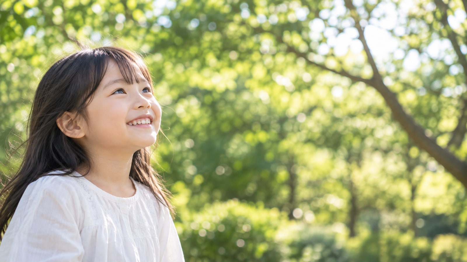 緑の中で笑顔を見せる子どものイメージ